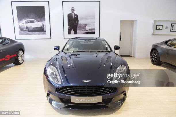 Photograph of actor Daniel Craig as James Bond is displayed on a wall behind an Aston Martin Vanquish luxury automobile on display at an Aston Martin...