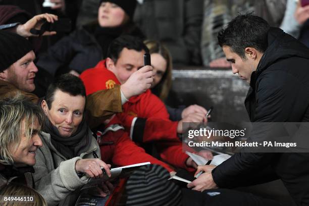 Manchester United's Robin van Persie signs autographs for fans pitchside at Old Trafford