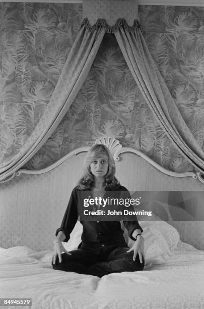 British actress Susan George sits cross-legged on a large bed, 26th February 1978.