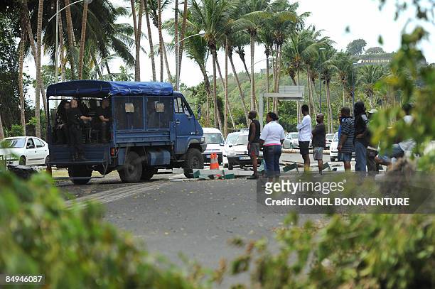 Locals look at policemen, on February 20, 2009 in Pointe-a-Pitre, on the French Caribbean island of Guadeloupe, near a barricade on a urban motorway...