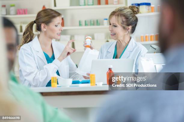 confident female pharmacist gestures while talking with a colleague - pharmaceutical compounding stock pictures, royalty-free photos & images