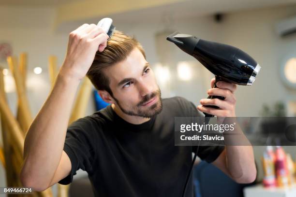 weibliche friseur kämmen und trocknen seine eigenen haare im friseursalon - haare mann stock-fotos und bilder
