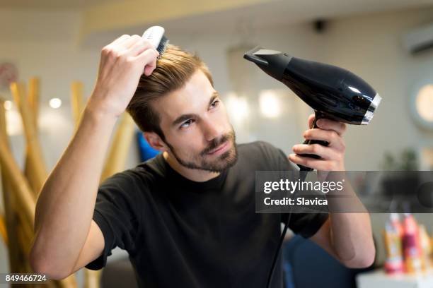 female hairdresser combing and drying his own hair in hair salon - hair comb stock pictures, royalty-free photos & images