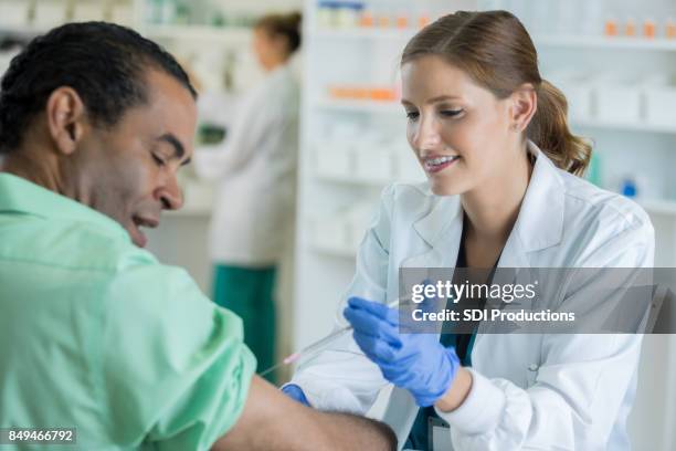 confident doctor gives male patient an injection - pharmacy vaccination stock pictures, royalty-free photos & images