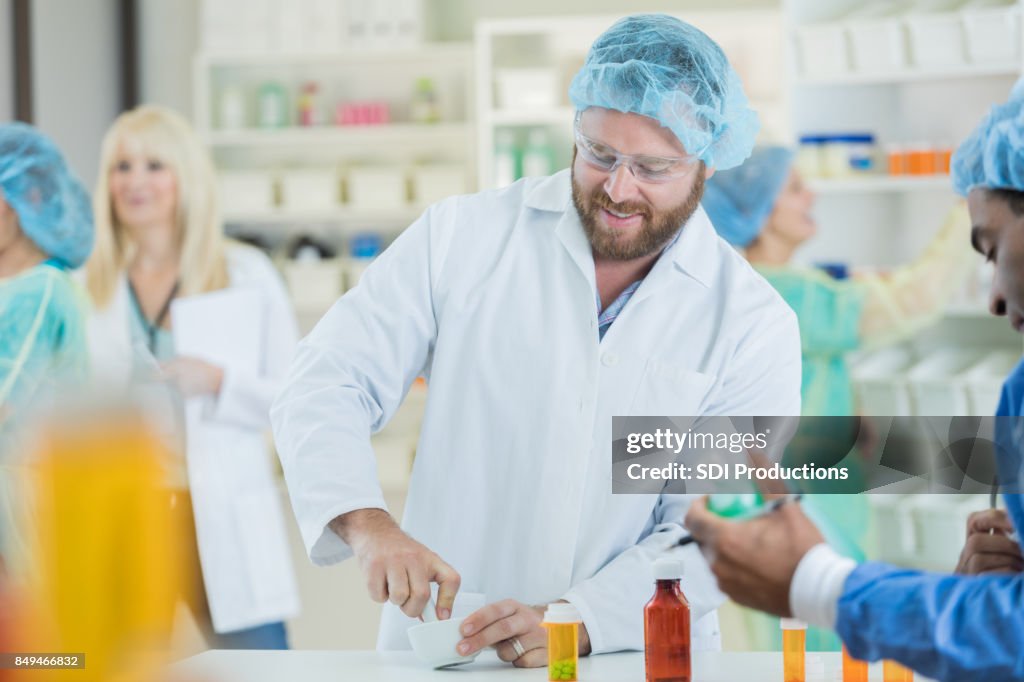 Bearded male pharmacist mixes patient's specialty medication