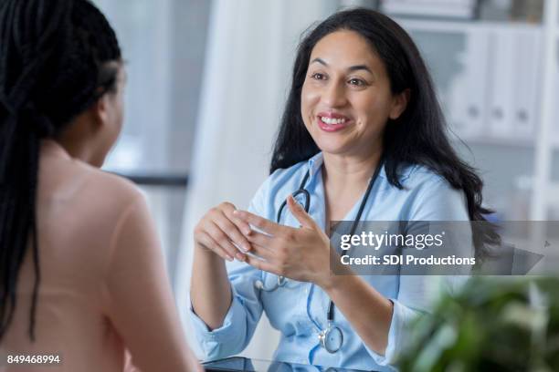 mid adult female doctor stays upbeat as she shares patient's diagnosis - mid adult patient stock pictures, royalty-free photos & images