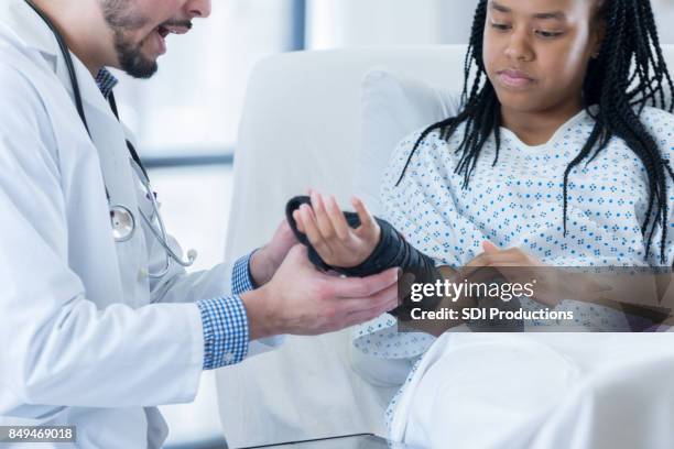 teen hospital patient learns how to wear wrist brace - african injured stock pictures, royalty-free photos & images