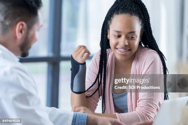 beautiful teenage girl views arm x-rays on laptop with physician - wrist stock pictures, royalty-free photos & images