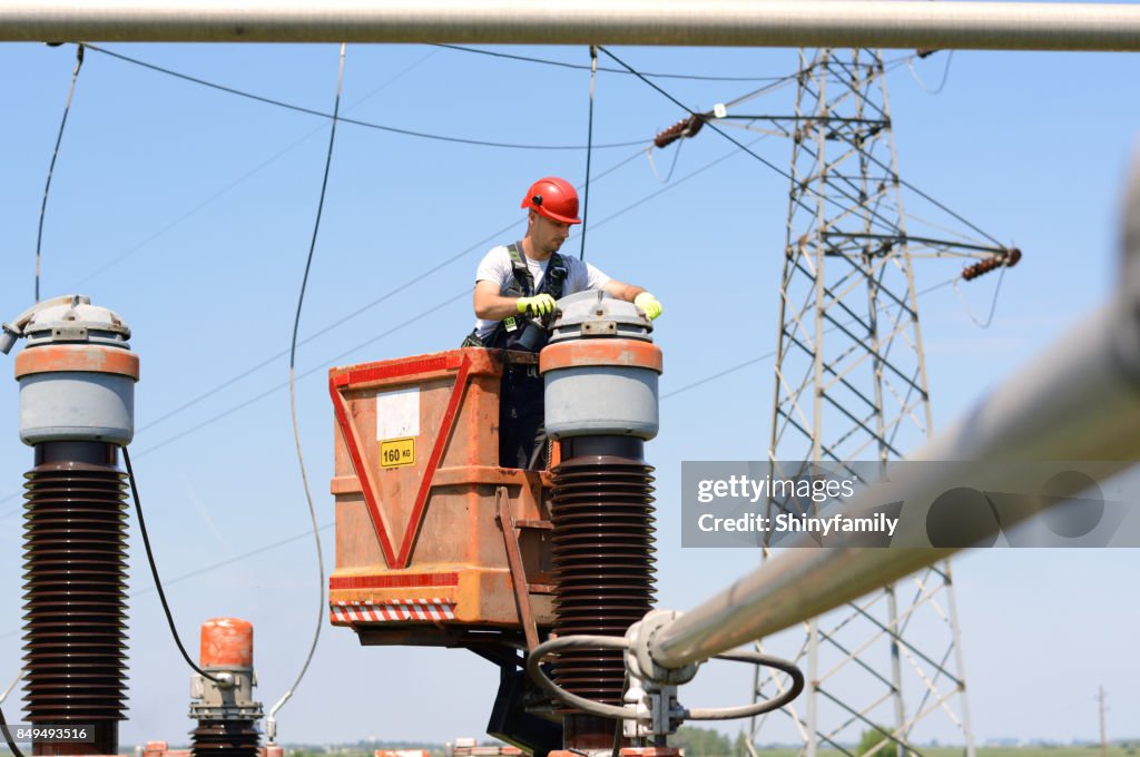 Electrician fixing power lines in power substation. Working in high.