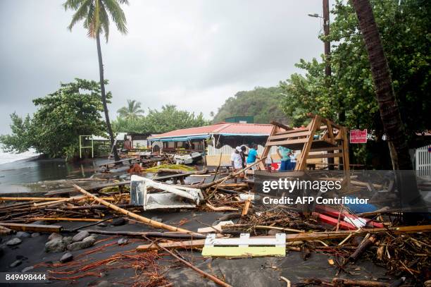 People stand next to debris at a restaurant in Le Carbet, on the French Caribbean island of Martinique, after it was hit by Hurricane Maria, on...