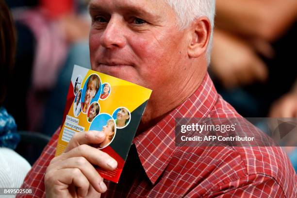 Supporter of German Chancellor and Christian Democratic Union's main candidate Angela Merkel holds an election campaign flyer during an election...