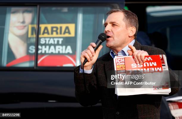 Deputy chairman of Germany's right extremist NPD party, Udo Pastoers speaks in a microphone as German Chancellor and Christian Democratic Union's...