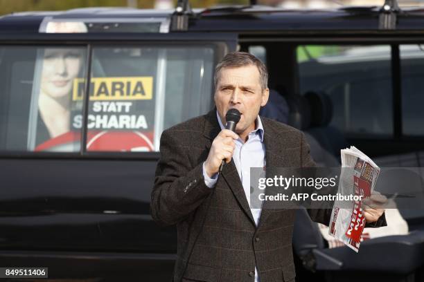 Deputy chairman of Germany's right extremist NPD party, Udo Pastoers speaks in a microphone as German Chancellor and Christian Democratic Union's...