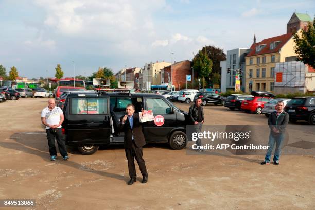 Deputy chairman of Germany's right extremist NPD party, Udo Pastoers speaks in a microphone as German Chancellor and Christian Democratic Union's...