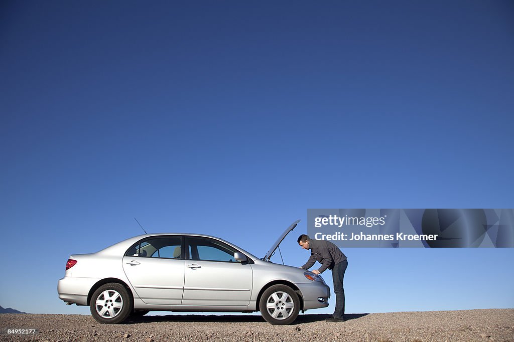 Man looking under hood of car