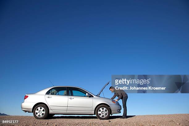 man looking under hood of car - vehicle breakdown stock pictures, royalty-free photos & images