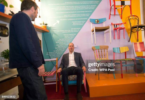 Prince William, Duke of Cambridge tries out a finished chair, which was restored as part of the theraputic process during a visit to the Spitalfields...