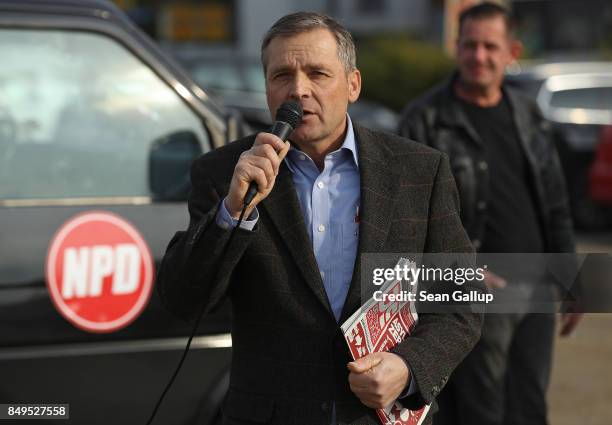 Udo Pastoers, a member of the far-right NPD political party, speaks outside the venue where German Chancellor and Christian Democrat Angela Merkel...