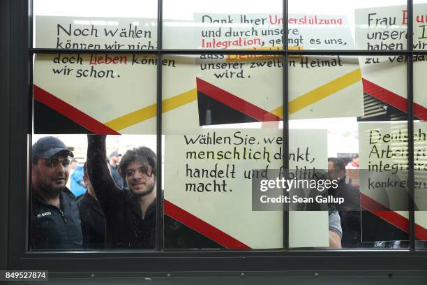 Refugees from Syria hold up signs directed favourably to German Chancellor and Christian Democrat Angela Merkel as they stand outside the hall where...