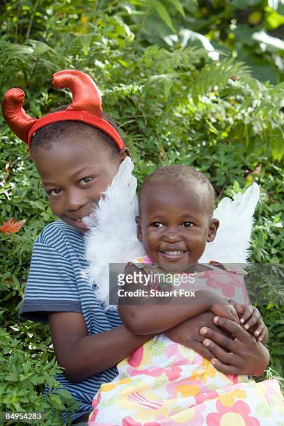 young boy wearing devil horns holds his younger sister on his lap, kwazulu natal province, south africa - zulu girls 個照片及圖片檔