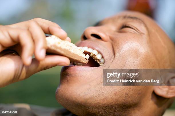 man eating a health bar. pietermaritzburg, kwazulu-natal province, south africa - black man eating stock pictures, royalty-free photos & images