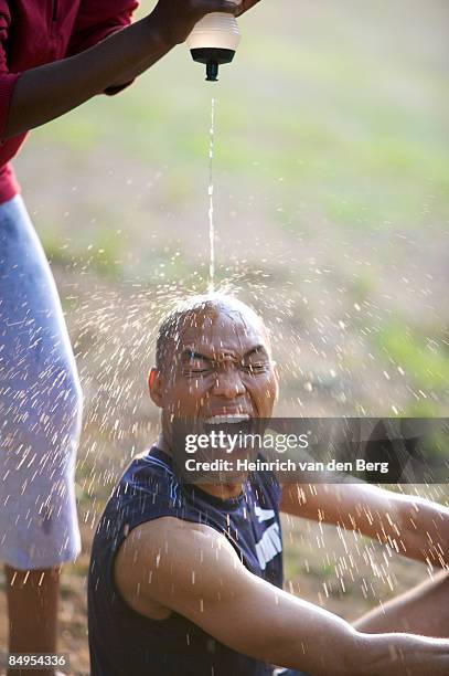 woman pouring water over a man's head. pietermaritzburg, kwazulu-natal province, south africa - freek van den bergh stock pictures, royalty-free photos & images