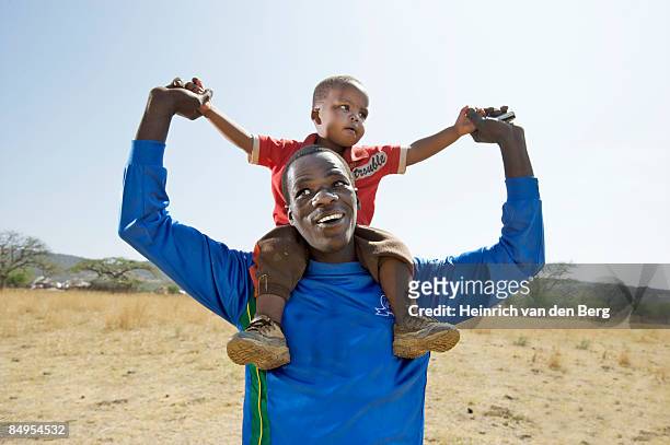 man carrying his child on his shoulders. winterton, kwazulu-natal province, south africa - freek van den bergh stock pictures, royalty-free photos & images