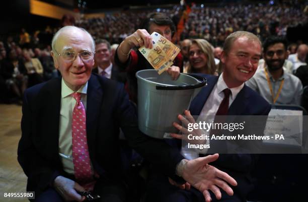 Menzies Campbell and Tim Farron hold a bucket as a delegate puts a donation of Euros in at the Liberal Democrats annual conference at the Bournemouth...