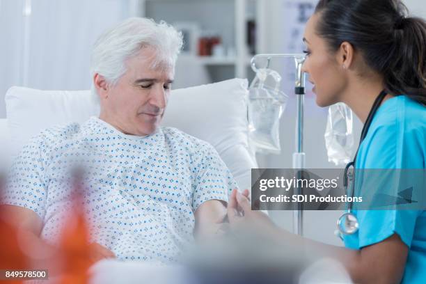 female doctor talks with male patient - hospital bed with iv stock pictures, royalty-free photos & images