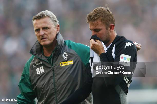 Christoph Kramer of Moenchengladbach gets lead off the pitch to be treated for an injury by Dr. Stefan Hertl during the Bundesliga match between...