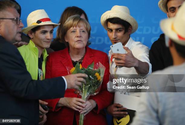 German Chancellor and Christian Democrat Angela Merkel poses for a photo with Syrian refugees after she spoke at an election campaign stop on...