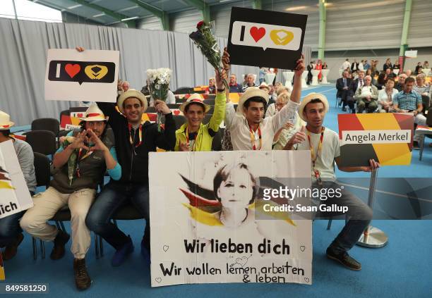 Refugees from Syria hold up signs, including a large one that reads: "We love you. We want to stoday, work and live." prior to the arrival of German...