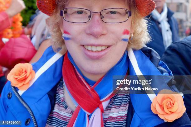 Woman with her cheeks painted with national flags of the Netherlands wait for the proceedings of Dutch King Willem-Alexander, Queen Maxima, Princess...