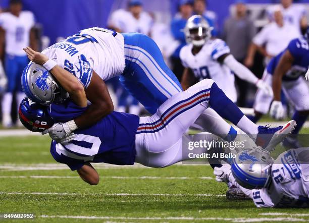Eli Manning of the New York Giants is tackled by Cornelius Washington of the Detroit Lions after an attempted pass in the fourth Quarter during their...