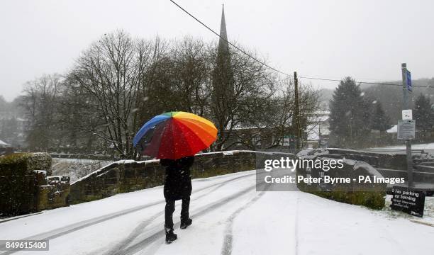 Woman crosses a bridge in Todmorden, West Yorkshire during as snow falls.