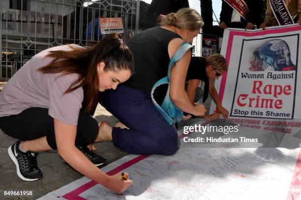 Foreign tourists participate in signature campaign to show their support towards crime against women and child abuse on September 19, 2017 in...