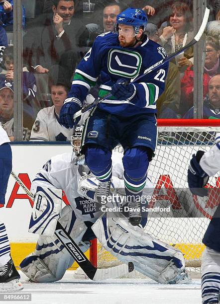 Vesa Toskala of the Toronto Maple Leafs is screened by a leaping Daniel Sedin of the Vancouver Canucks during their NHL game at the Air Canada Centre...