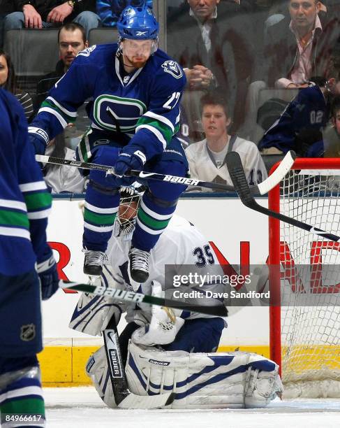 Vesa Toskala of the Toronto Maple Leafs is screened by a leaping Daniel Sedin of the Vancouver Canucks during their NHL game at the Air Canada Centre...