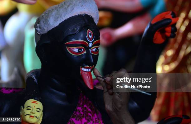 An indian artisan gives final touch to the clay idols of Indian hindu Goddess Kali,in a workshop , ahead of Navratri and Durga pooja festival , in...