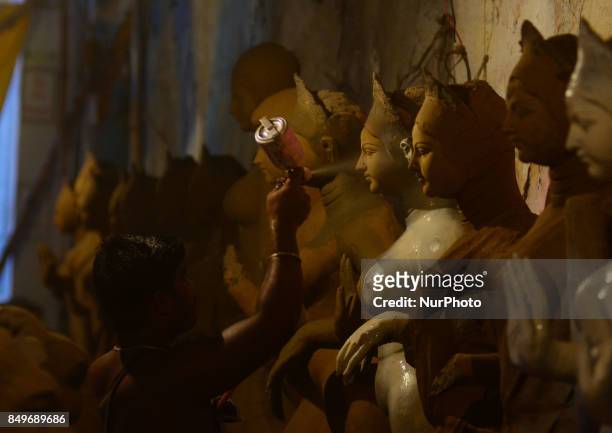 An indian artisan sprays color to give a decorative touch to the clay idols of Indian hindu Goddess Durga ,in a workshop , ahead of Navratri and...