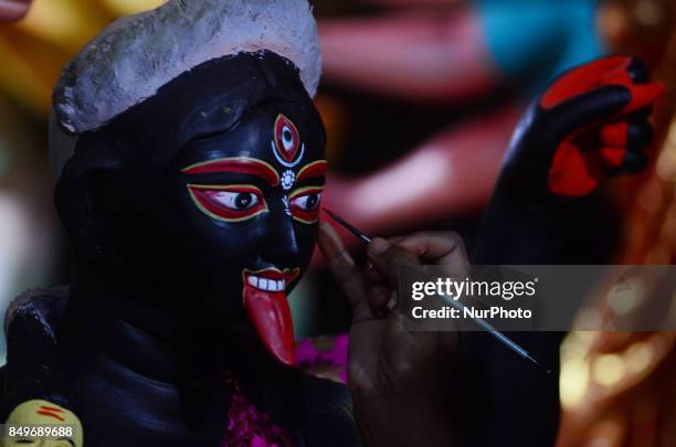 An indian artisan gives final touch to the clay idols of Indian hindu Goddess Kali,in a workshop , ahead of Navratri and Durga pooja festival , in...