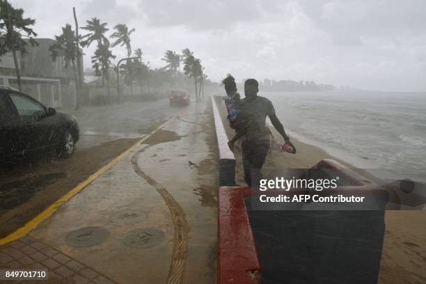 Man and his daughter flee from the rain on a beach in San Juan, Puerto Rico, on September 19 prior to the arrival of Hurricane Maria. Maria headed...