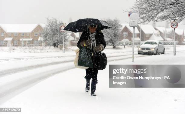 Woman struggles in the cold conditions in Wallsend near Newcastle as snow and sleet hit parts of north England today as freezing winds sweep across...