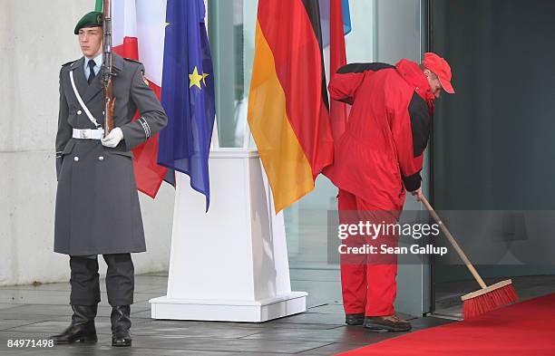 Worker sweeps the red carpet at the Chancellery before the arrival of European Union leaders for a meeting on February 22, 2009 in Berlin, Germany....