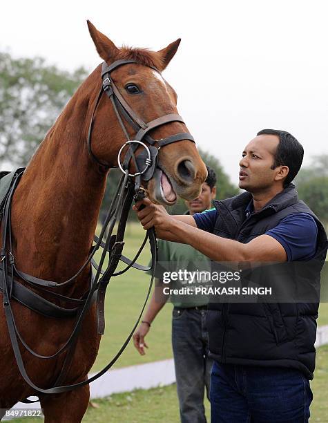 Member of Parliament and industrialist Naveen Jindal checks the reins on a horse prior to the polo finals match between Jindal Steel & Power against...