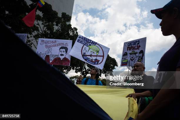 An attendee holds a sign, center, that reads "Hands Off Venezuela" with an illustration depicting U.S. President Donald Trump during a rally in...