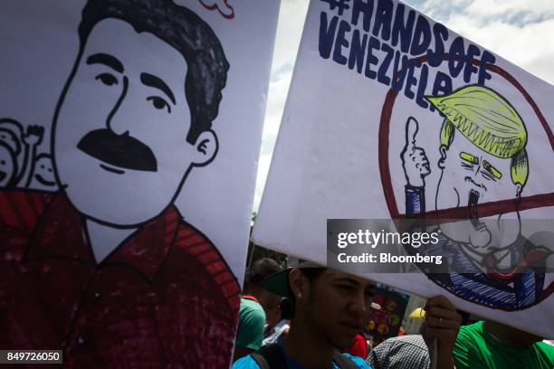 An attendee holds a sign that reads "Hands Off Venezuela" with an illustration depicting U.S. President Donald Trump during a rally in support of...