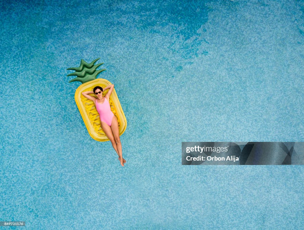 Carefree woman on inflatable pineapple