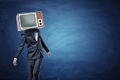 An unsteady businessman standing unevenly with a large retro TV on his head showing gray noise