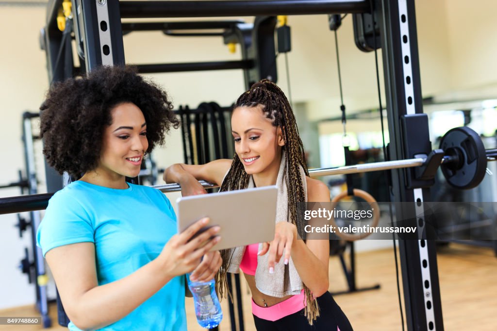 Two women using tablet in gym